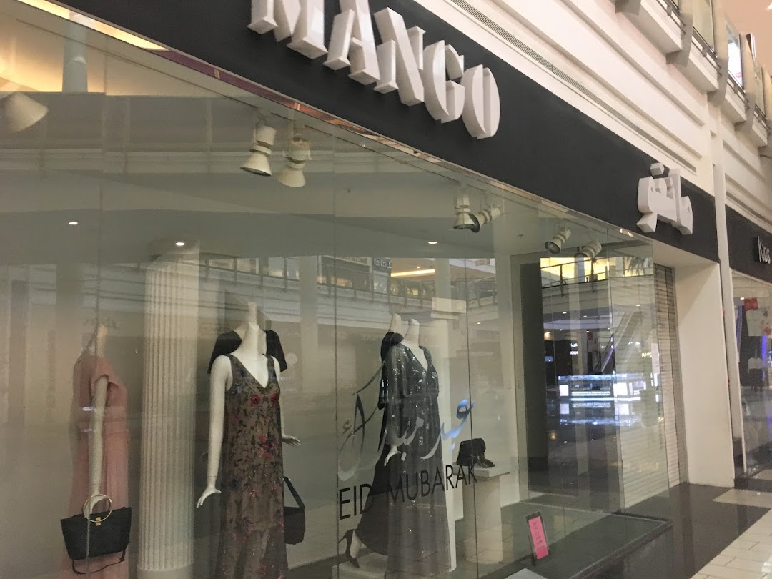 The exterior of a Mango clothing store with mannequins displaying dresses in the window.