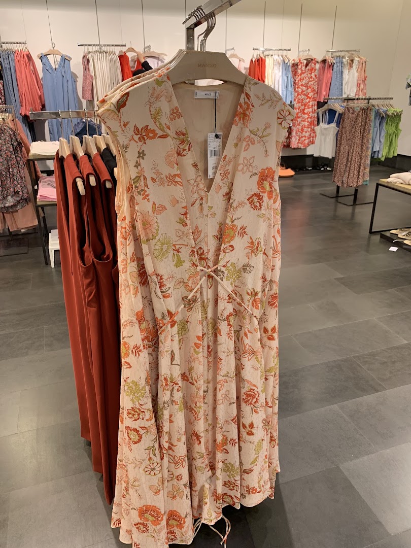 A floral print dress is displayed on a hanger in a clothing store.