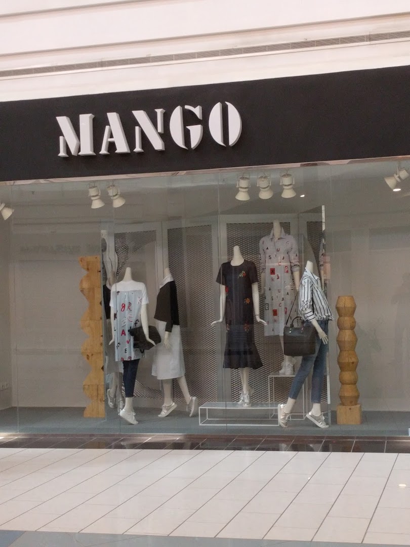 The Mango store front displays mannequins dressed in stylish outfits in the shop window.