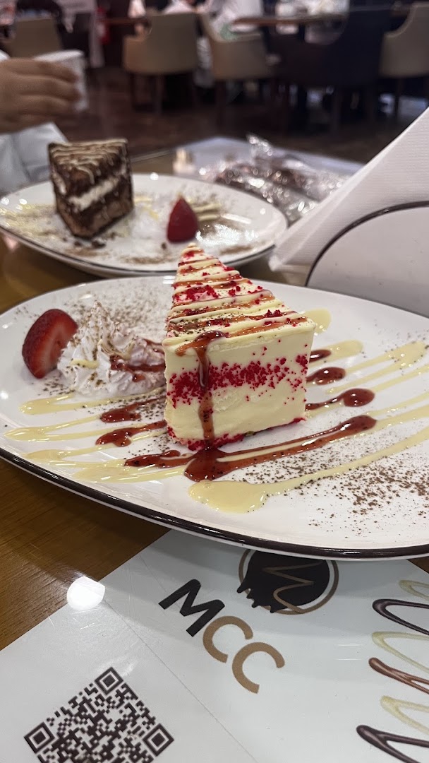 Two slices of cake, one red velvet and one chocolate, are beautifully presented on white plates with garnishes.