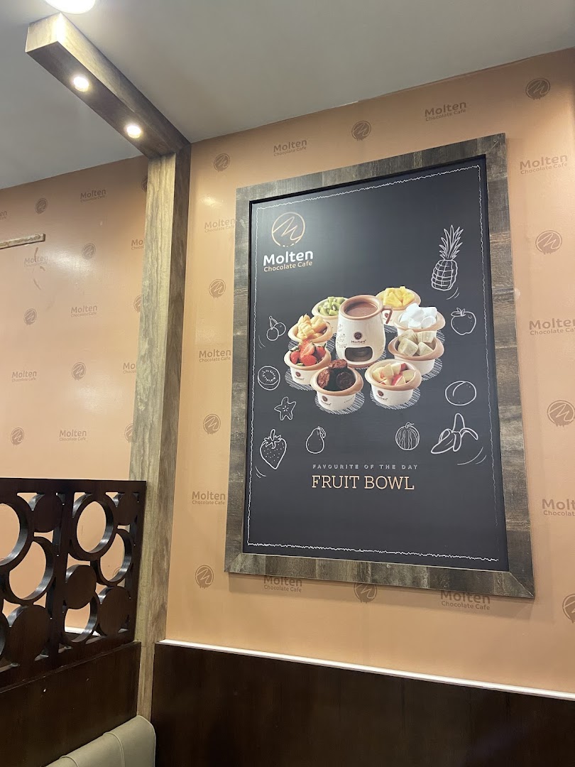 A framed chalkboard menu displaying a fruit bowl with various fruits and a chocolate fondue.