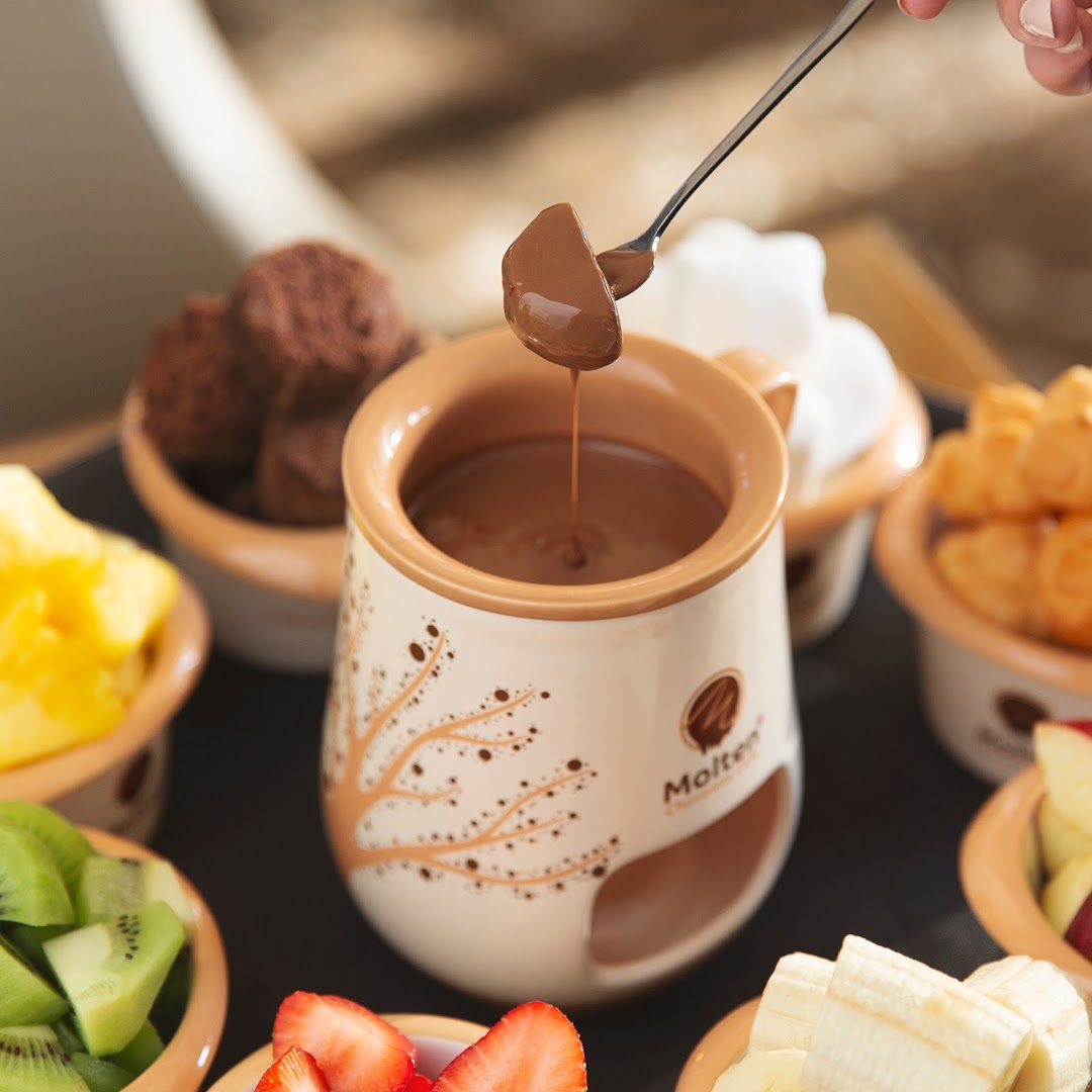 A chocolate fondue pot with various fruits and treats for dipping.
