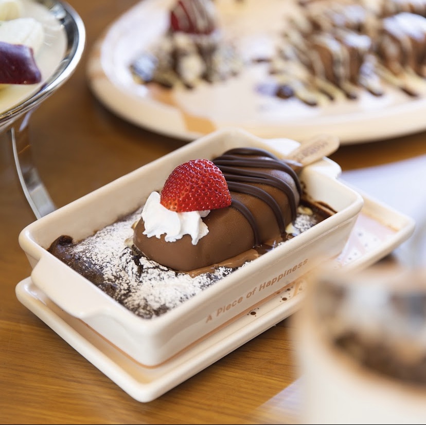 A delicious chocolate dessert with strawberry and whipped cream, dusted with powdered sugar.