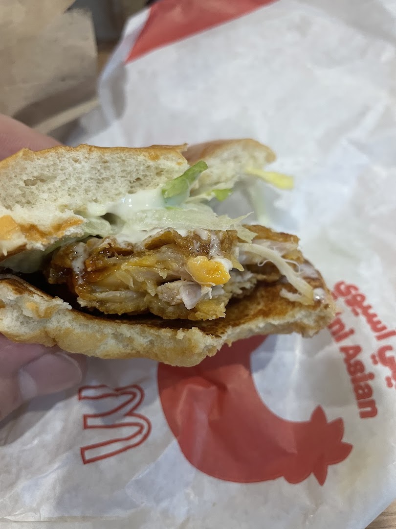 A close-up of a half-eaten chicken burger on McDonald's branded paper.