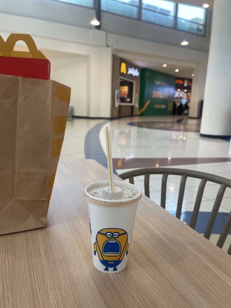 A McDonald's drink with a Minion design sits on a table next to a Happy Meal bag.