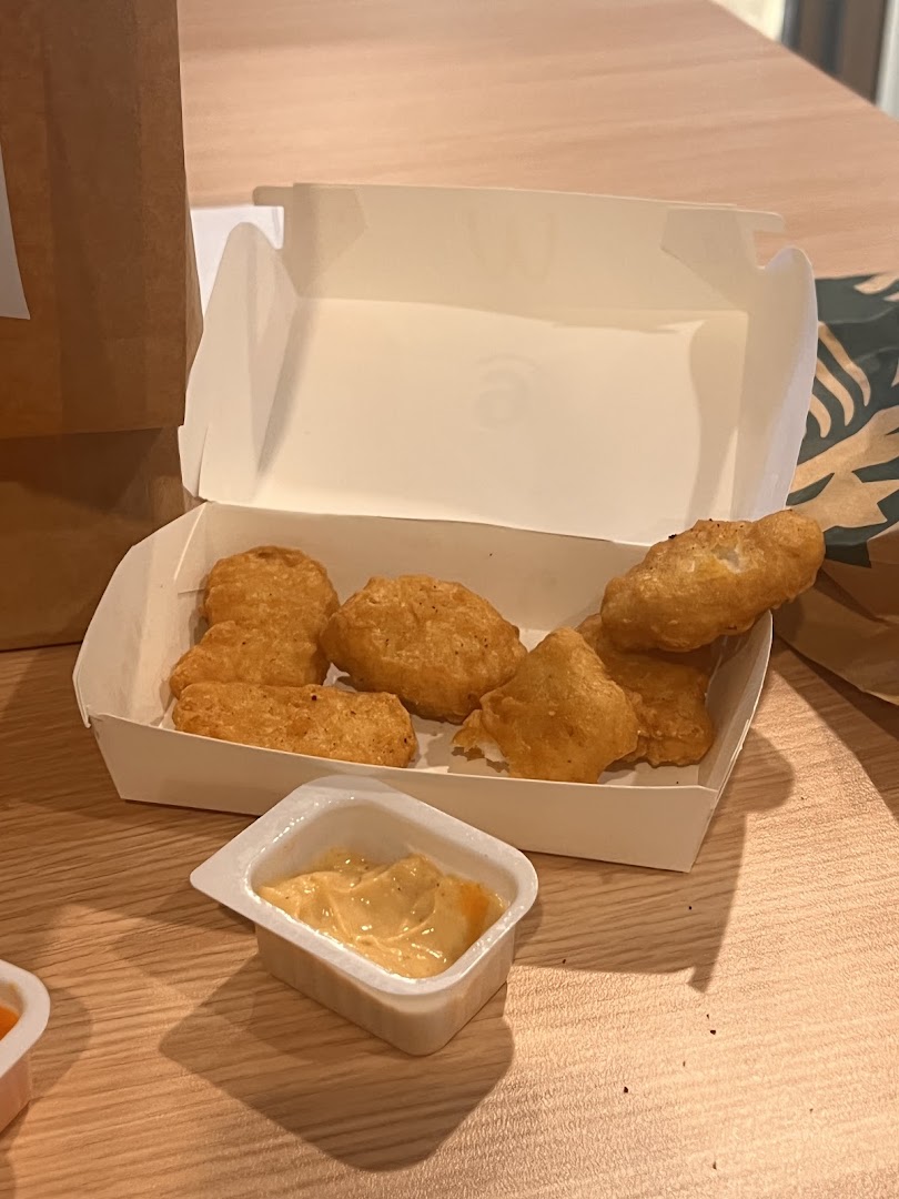 A box of McDonald's Chicken McNuggets with dipping sauce on a wooden table.