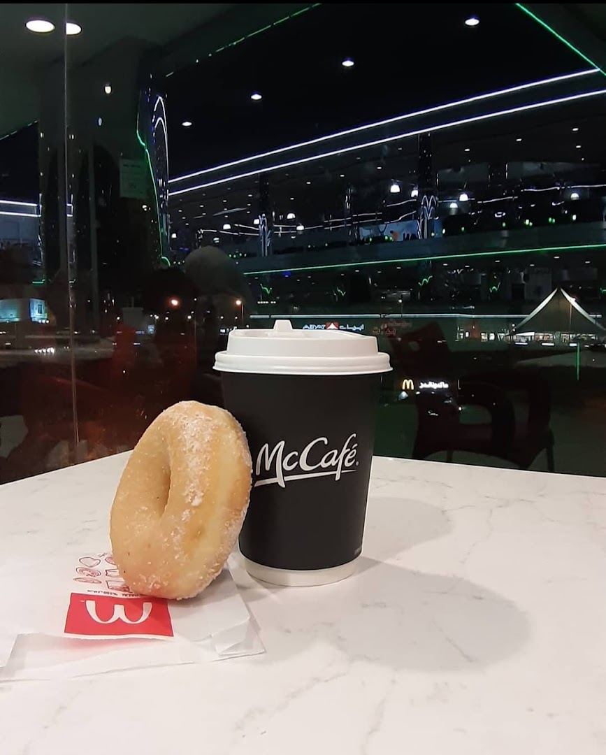 A McCafe coffee cup and a sugar-dusted donut on a marble table.