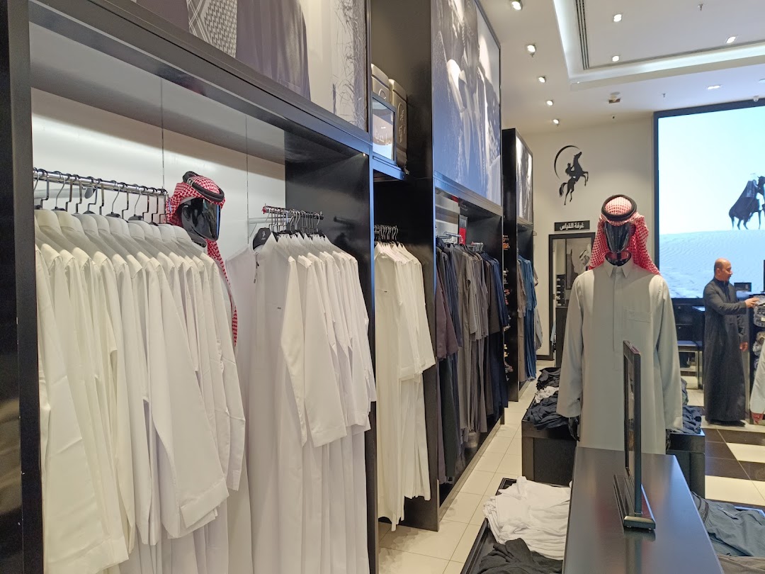 Interior view of a clothing store displaying traditional men's attire on mannequins and racks.