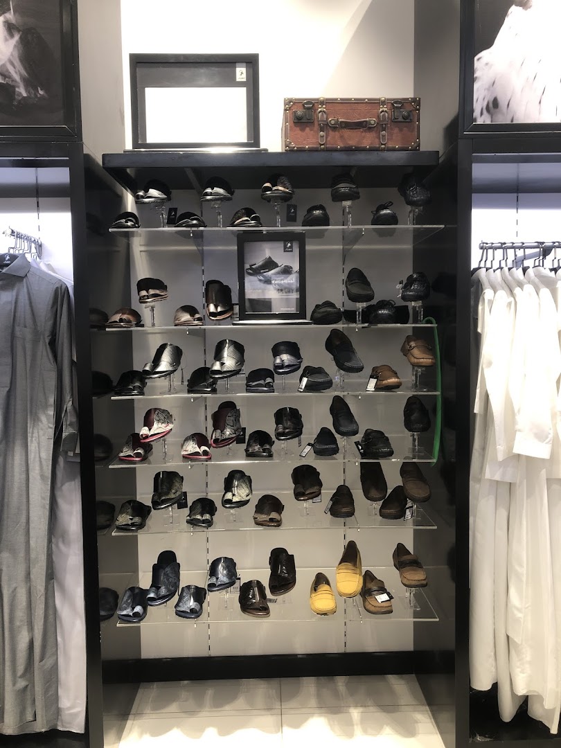 A well-lit display of men's shoes and traditional attire in a retail store.