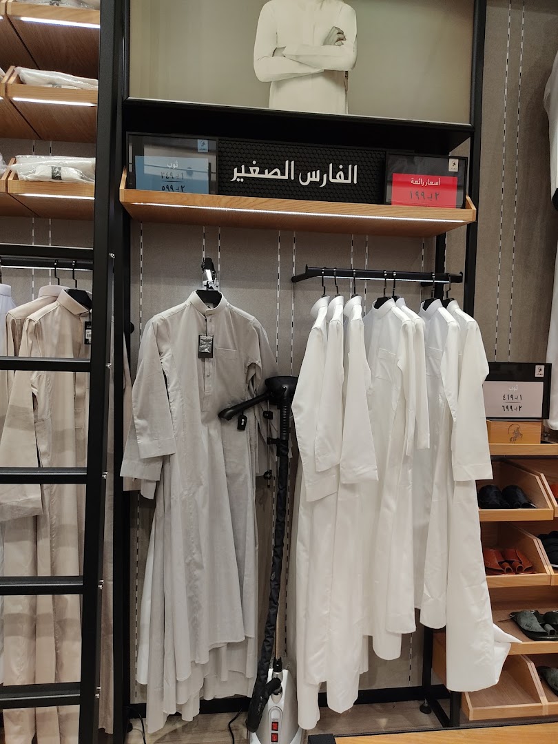 A display of traditional white thobes for men, neatly arranged on hangers.