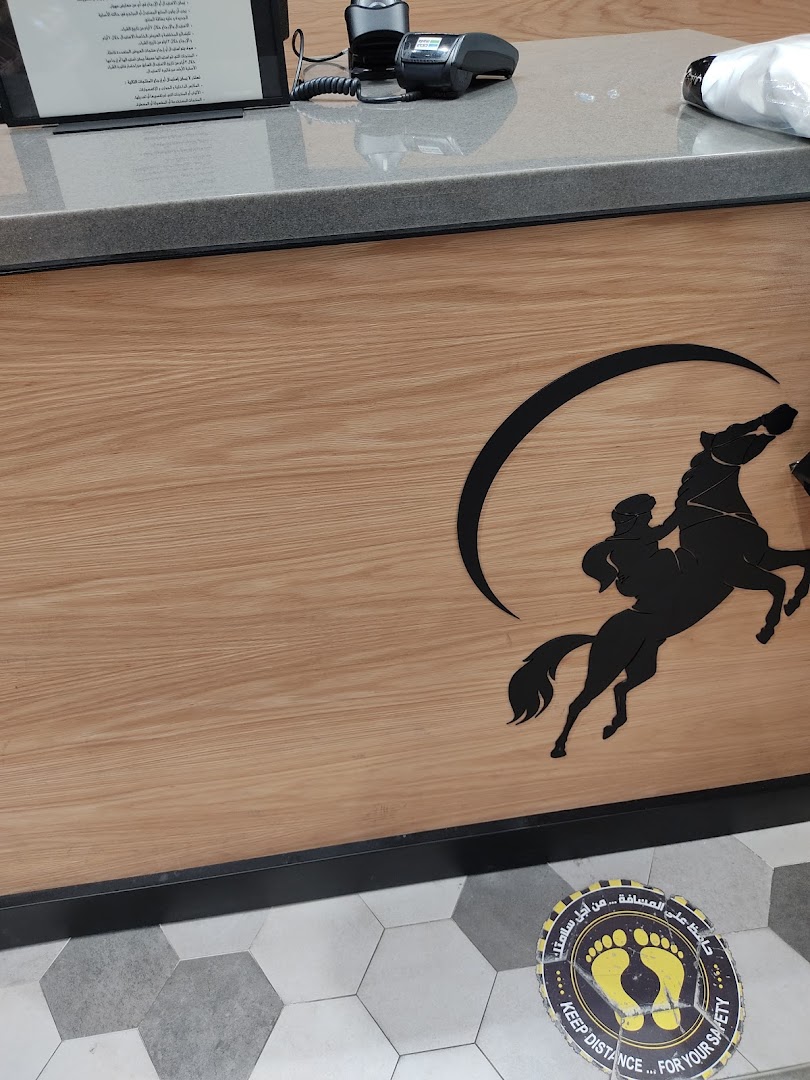 A wooden counter with a horse and rider logo and a social distancing sticker on the floor.