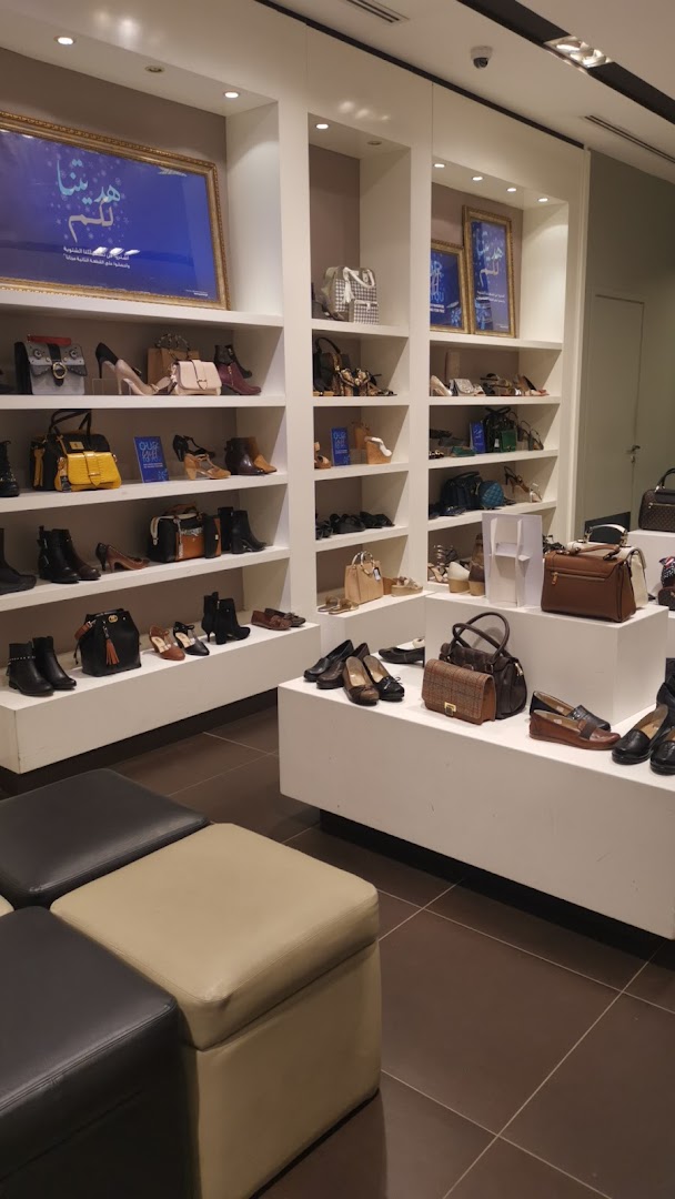 Interior view of a shoe and handbag store with shelves displaying various footwear and bags.