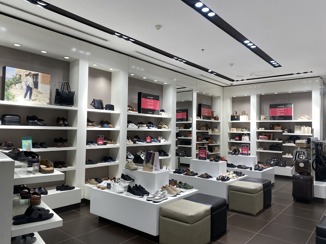 Interior view of a well-lit shoe and handbag store with shelves displaying various footwear and accessories.