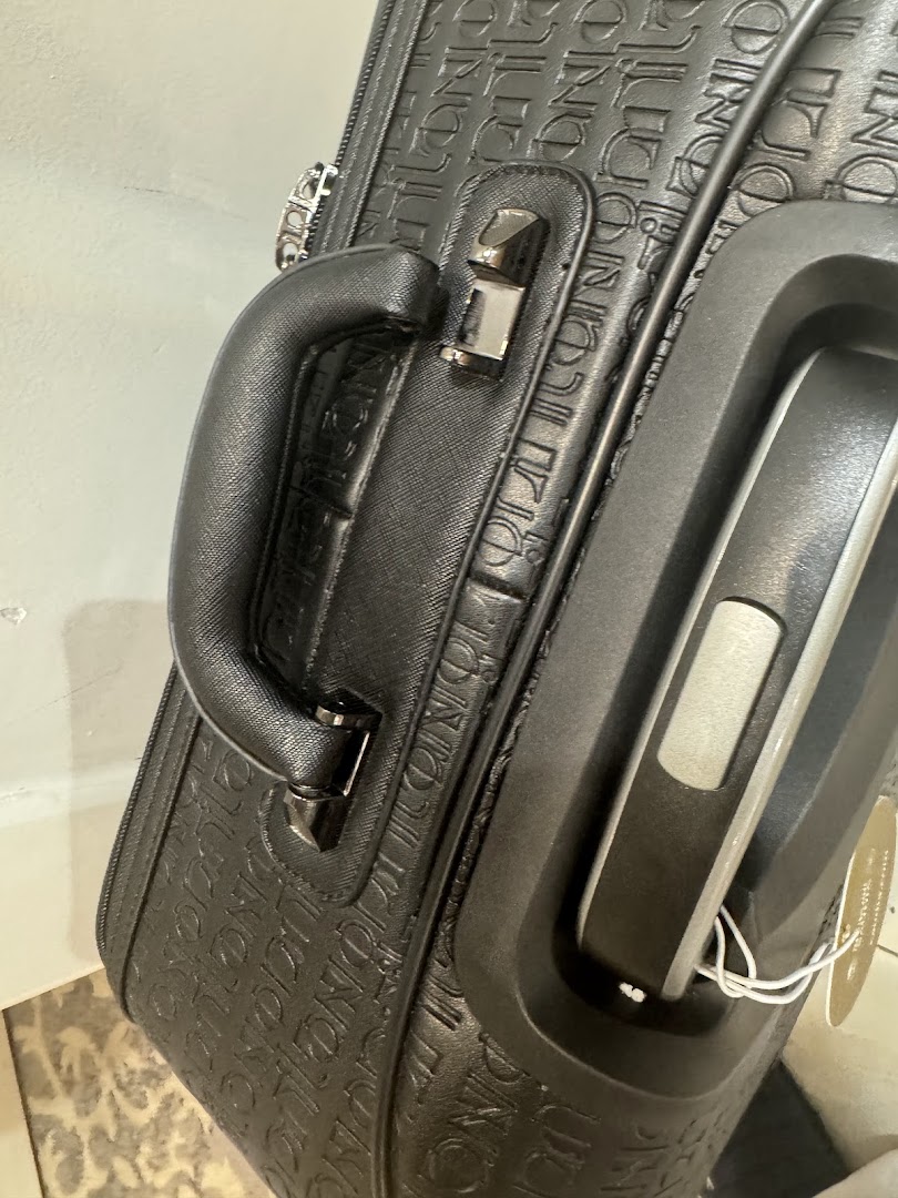 Close-up of a black suitcase with embossed branding and a sturdy handle.