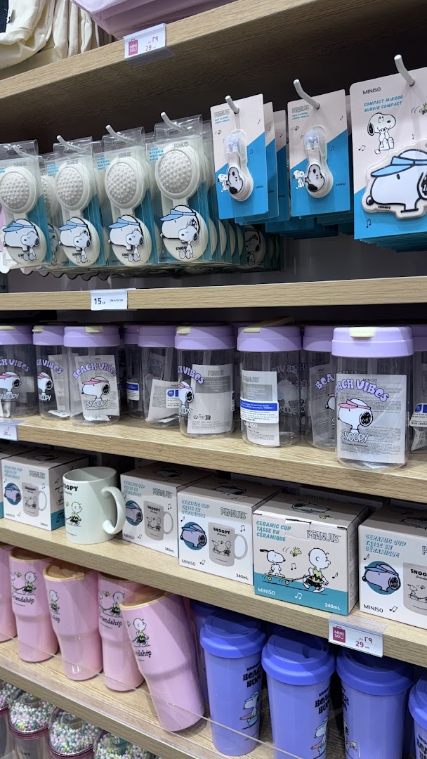 Shelves stocked with Snoopy-themed merchandise, including brushes, mirrors, cups, and tumblers.