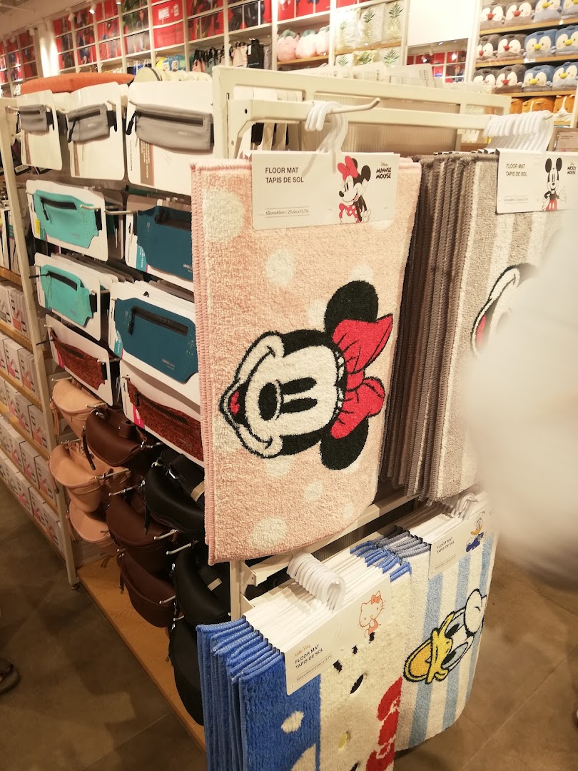 Interior view of a MINISO store showcasing various merchandise, including floor mats with cartoon characters.