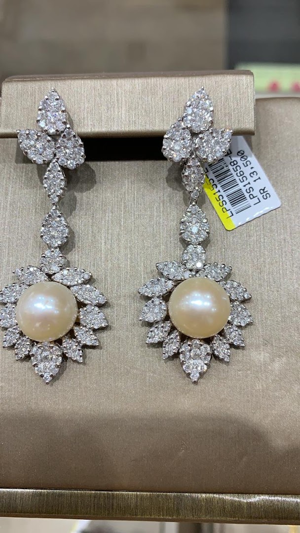 Exquisite pearl and diamond drop earrings displayed on a textured stand.