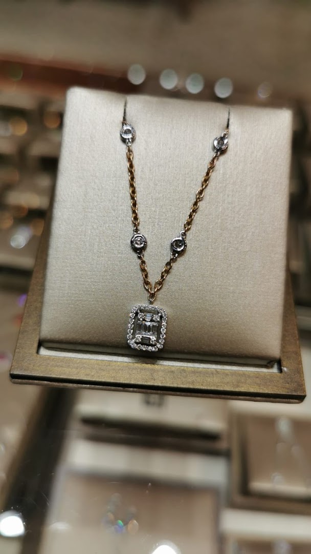A close-up shot of a diamond necklace with a rectangular pendant displayed on a beige stand.