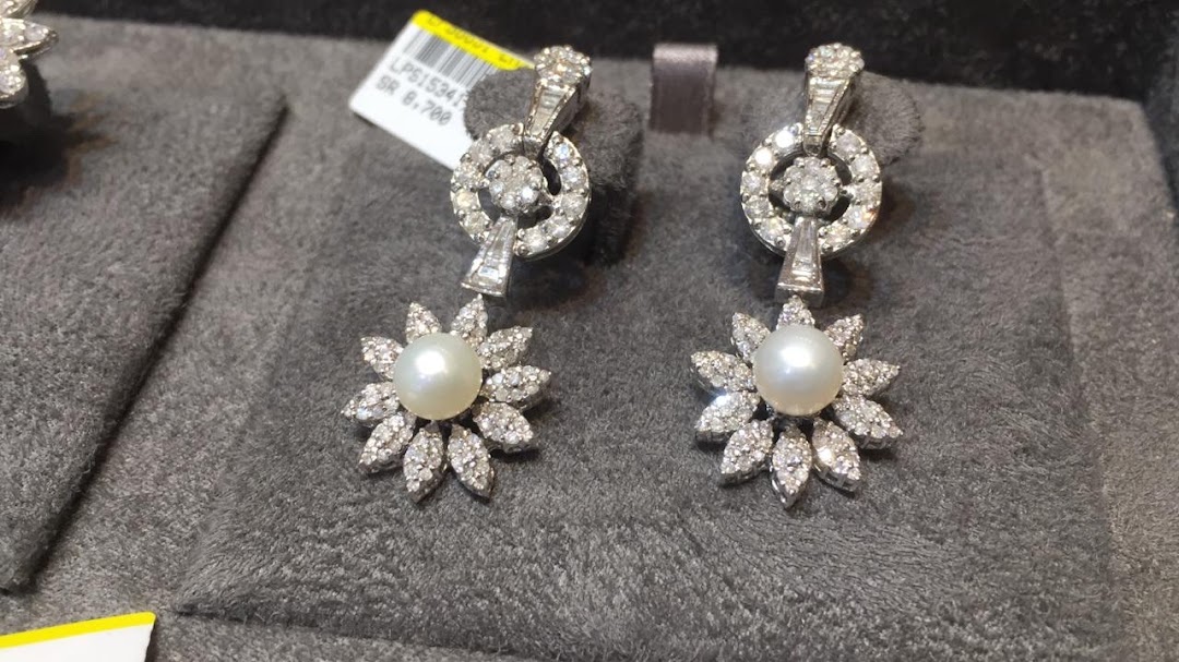 A pair of exquisite diamond and pearl drop earrings displayed on a grey velvet surface.