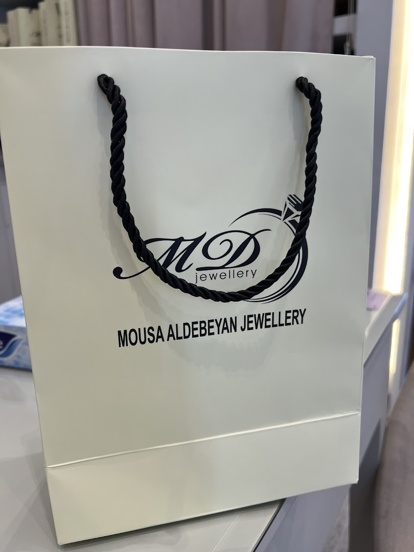 A white shopping bag with the logo and name of Mousa Aldebeyan Jewellery.