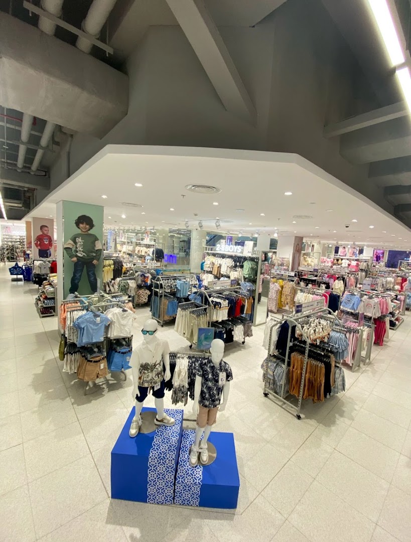 Interior view of a brightly lit clothing store with racks of children's apparel and mannequins.