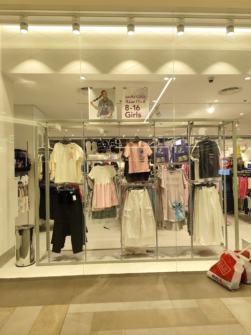 A shop window displaying girls' clothing for ages 8-16, featuring t-shirts and skirts.