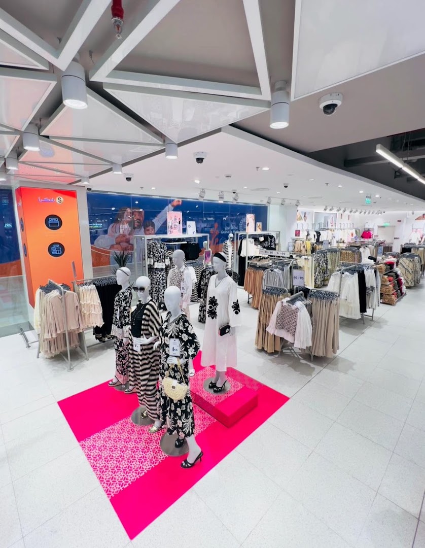 Interior view of a clothing store with mannequins displaying outfits and racks of apparel.