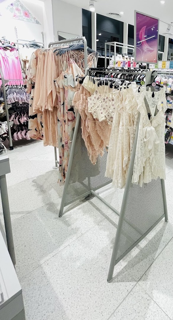 A display of women's sleepwear and lingerie in pastel colors on hangers.