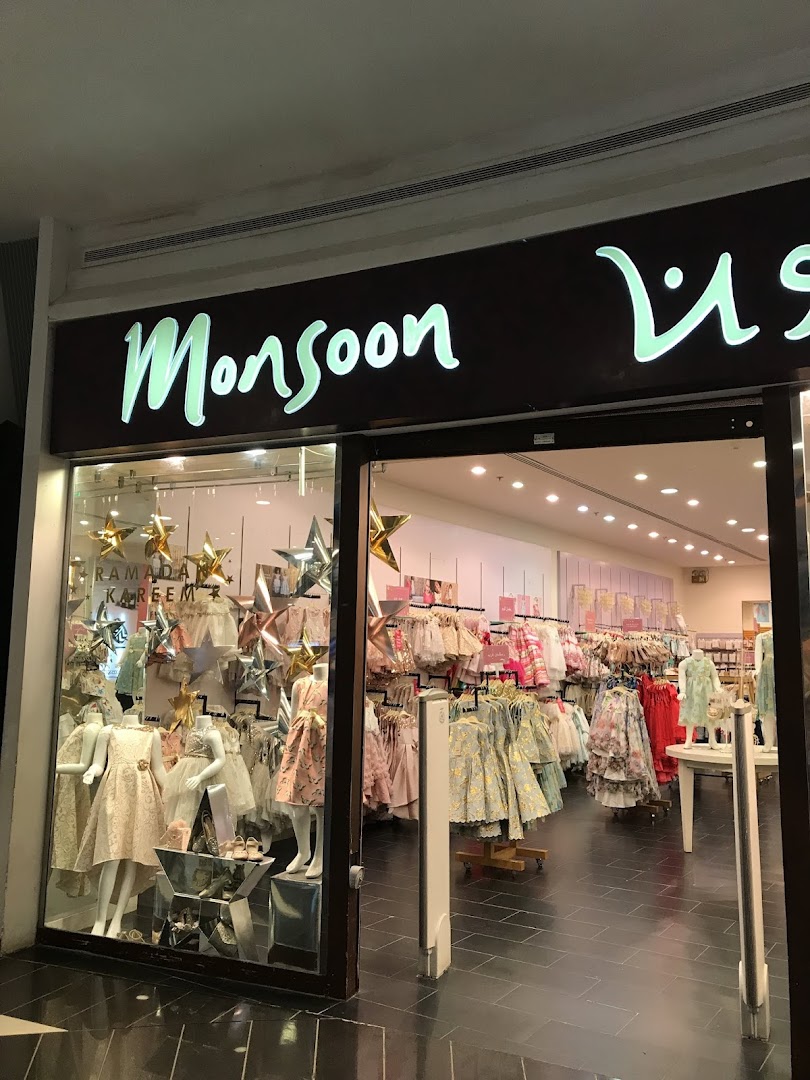 The entrance of a Monsoon Accessorize shop showcasing children's dresses and festive decorations.