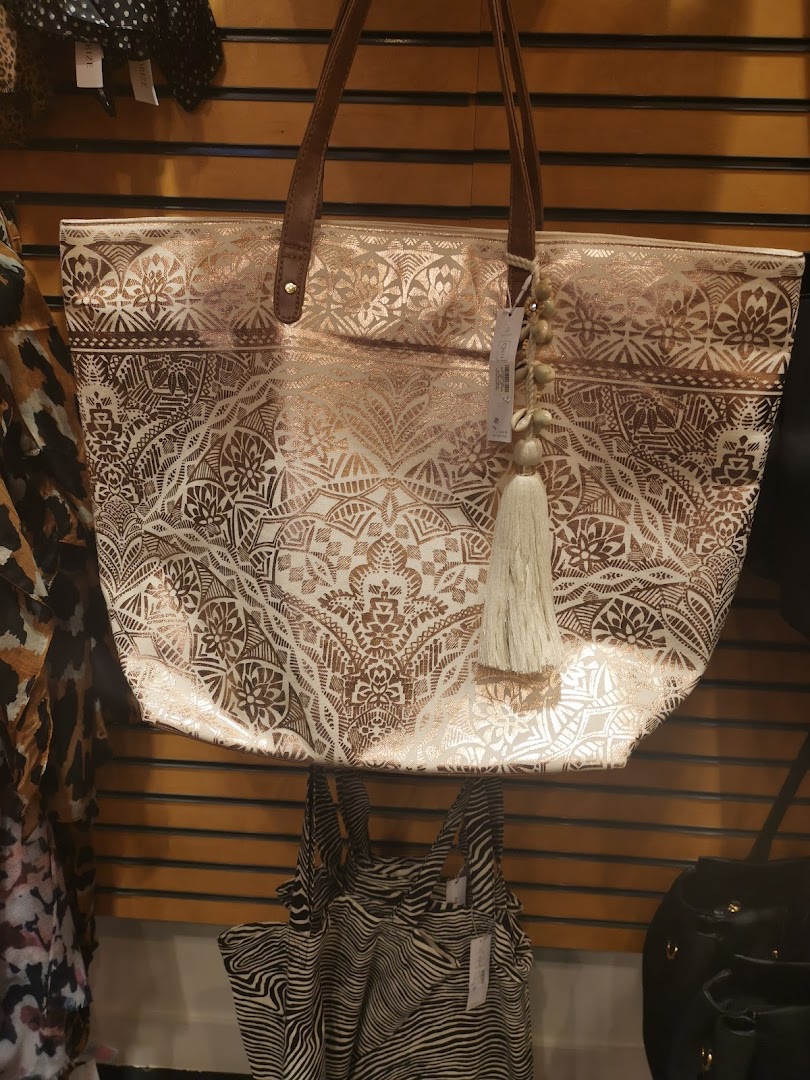 A large tote bag with a metallic rose gold pattern and a tassel hangs on a display.