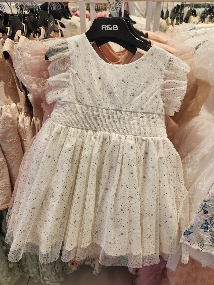 A close-up view of a white, sparkly dress with ruffled sleeves and a smocked waist.