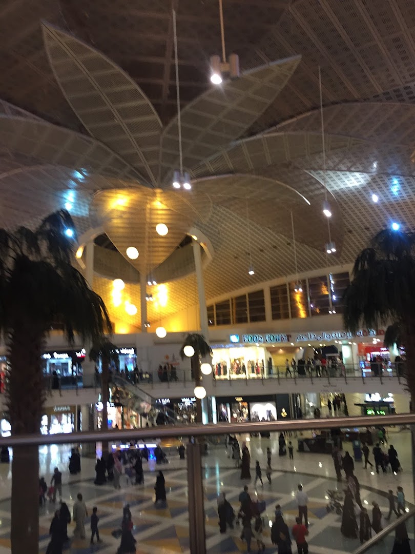 A bustling shopping mall interior with multiple levels, shops, and shoppers.