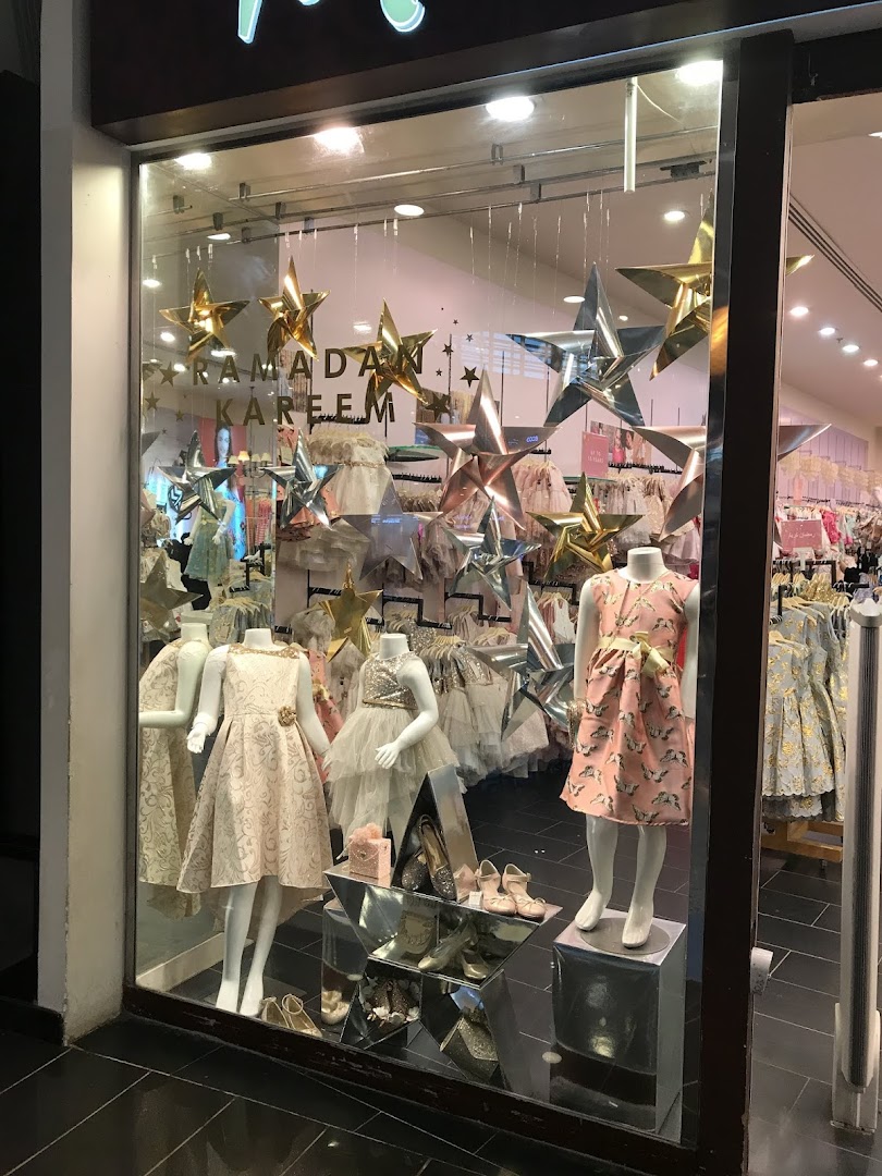 A shop window display featuring mannequins dressed in festive children's clothing and star decorations.