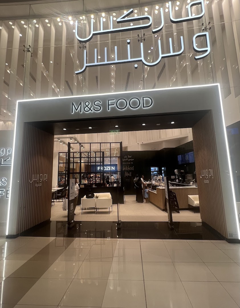 The entrance to an M&S Food store with Arabic and English signage.