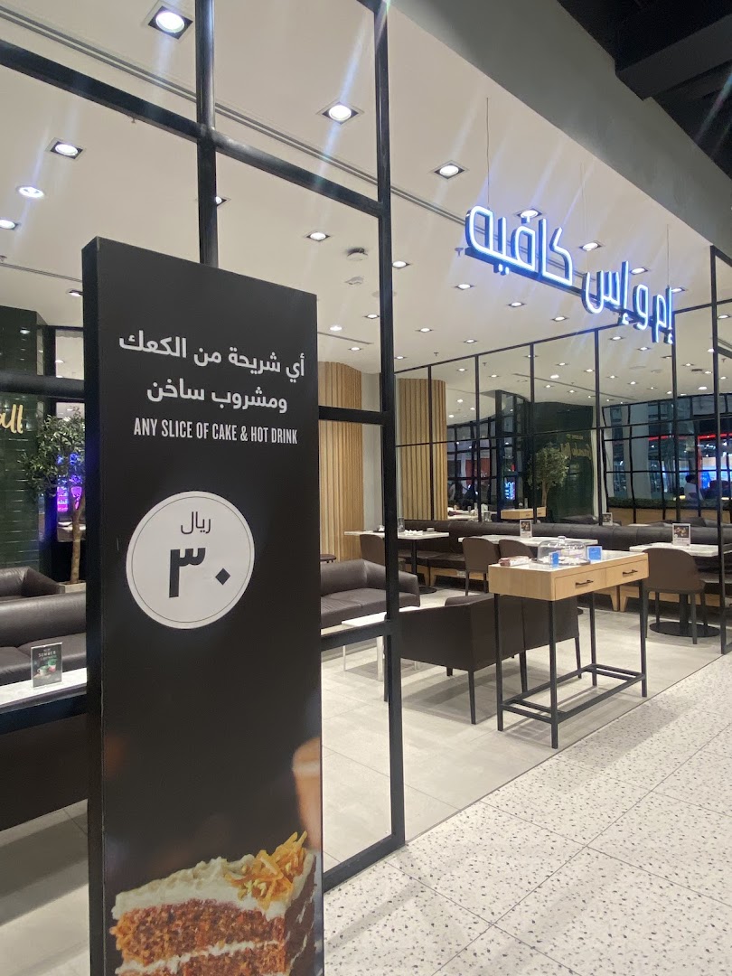 A sign outside a cafe advertises a slice of cake and hot drink for 30 riyals.