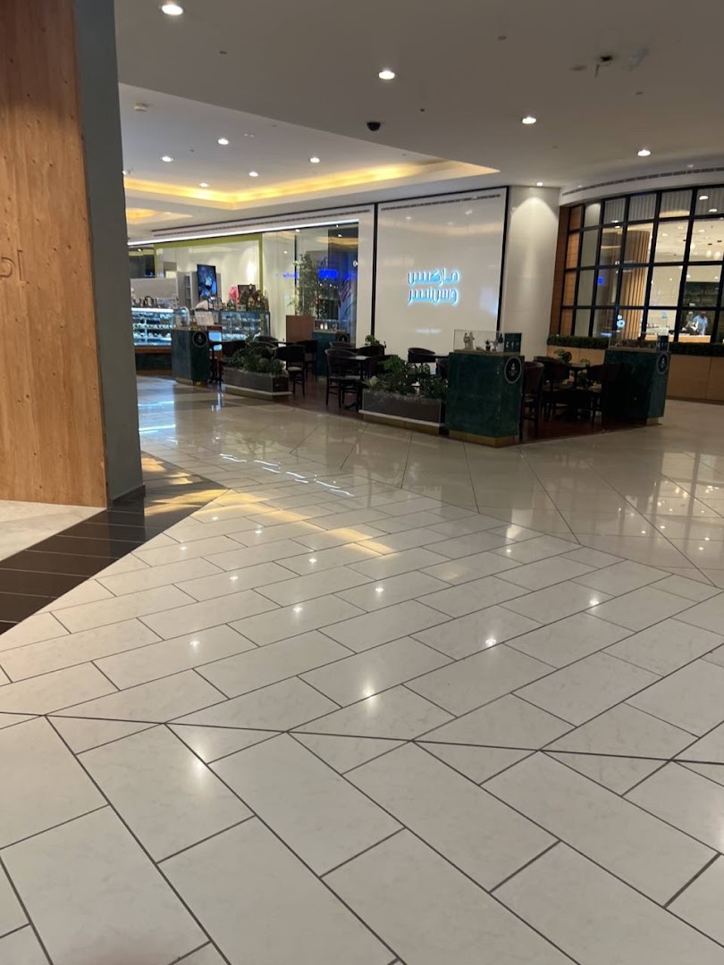 A cafe area with seating and display cases inside a modern shopping mall.