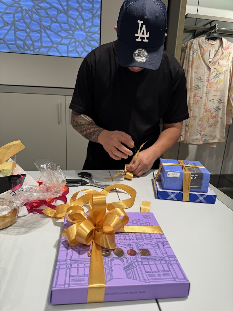 A person is wrapping gifts with golden ribbons in a store.