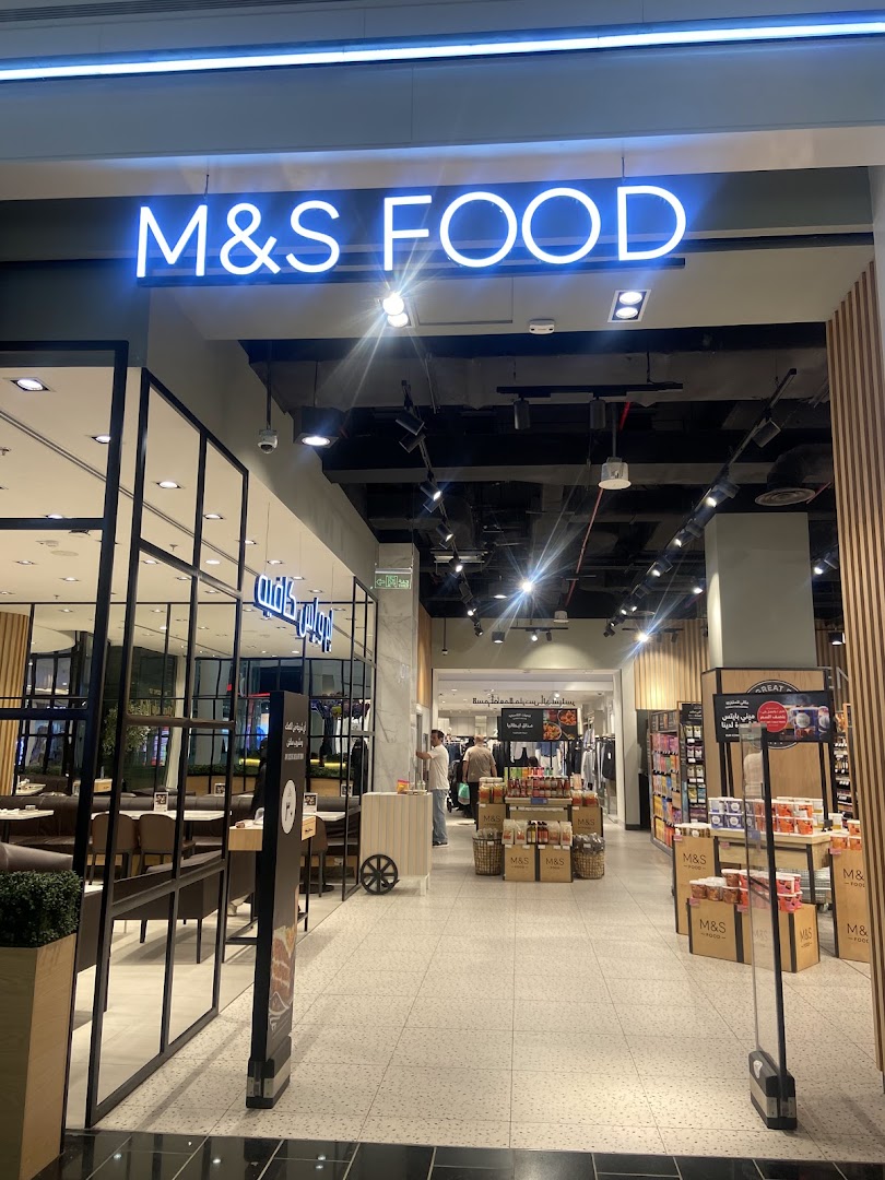 The entrance to an M&S Food store, showcasing a cafe area and food products.