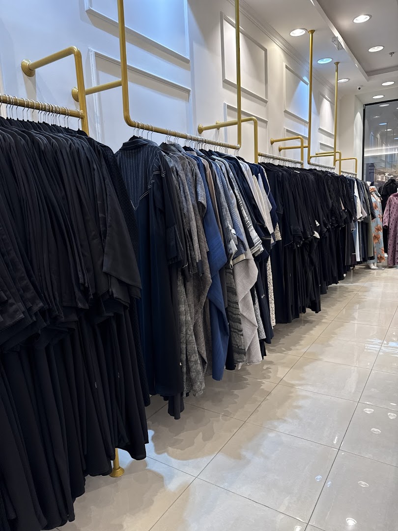 A row of elegant abayas and modest wear displayed on gold racks inside a boutique.