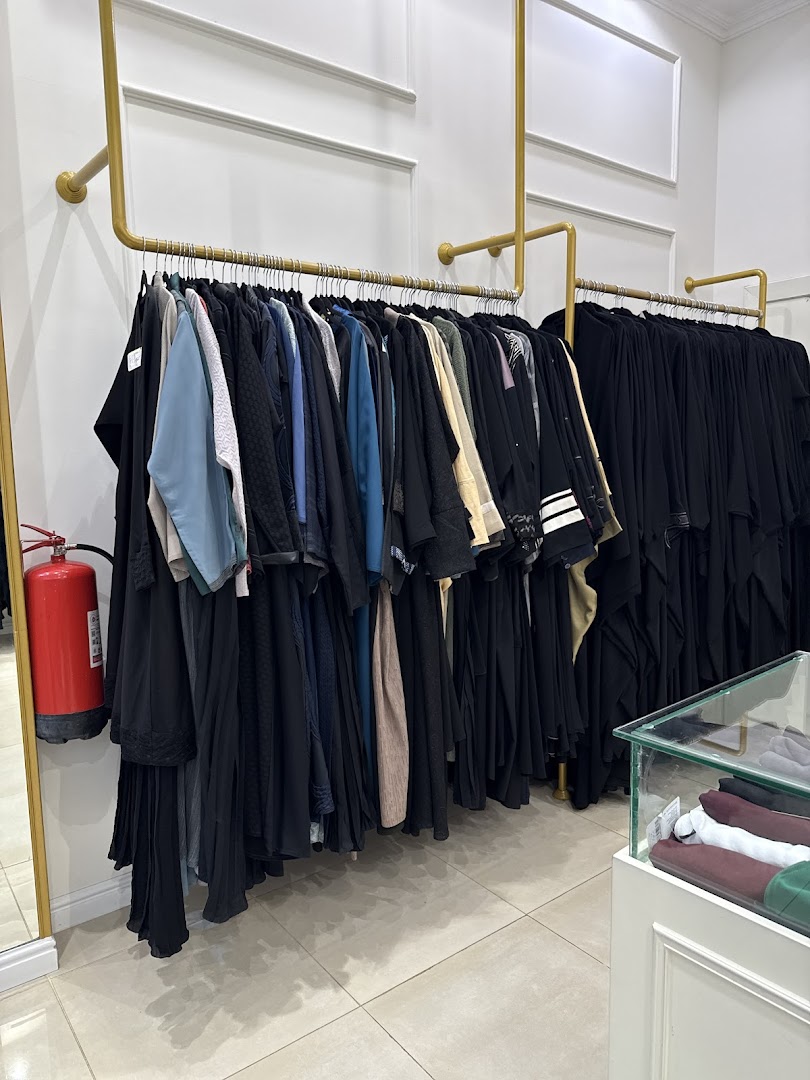 A clothing store interior with racks of abayas and other garments displayed.