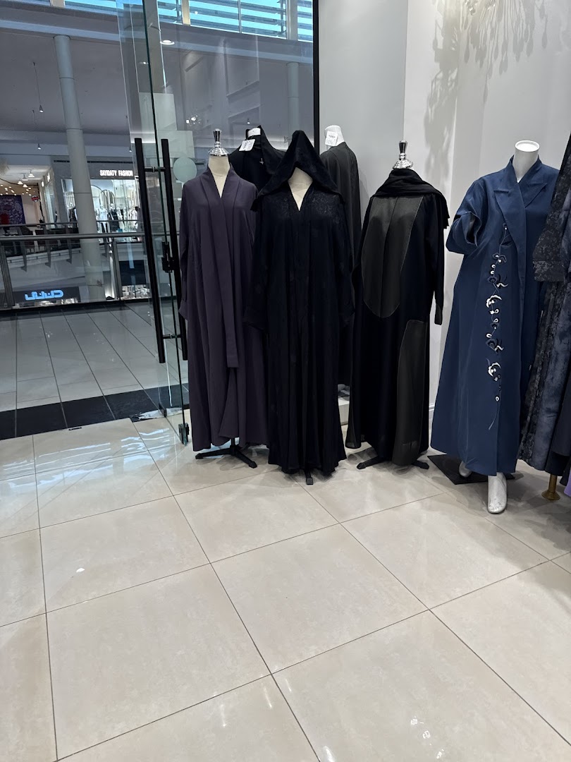 Mannequins display elegant abayas in various colors and styles inside a fashion boutique.