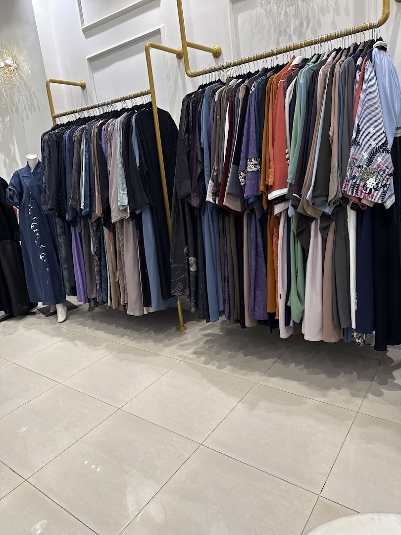 A clothing store interior with racks of stylish abayas and dresses in various colors and designs.