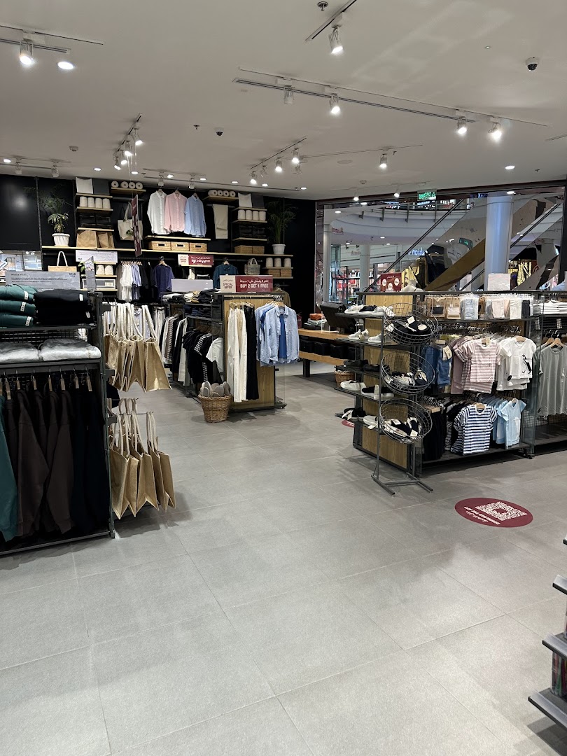 Interior view of a Muji store showcasing clothing, bags, and home goods.
