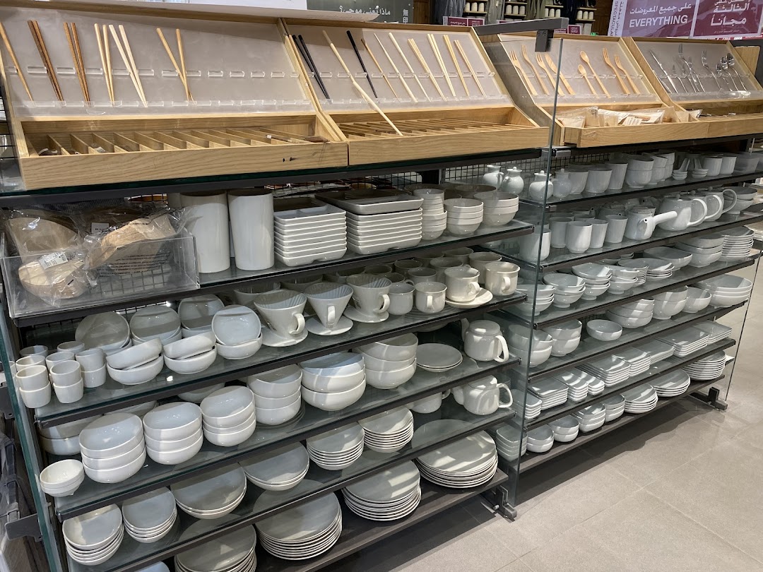 Shelves stocked with a wide variety of white and grey ceramic tableware and kitchenware.