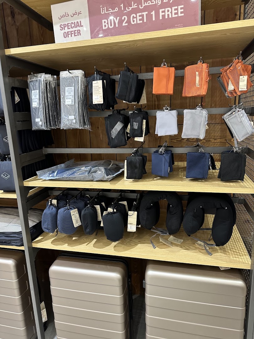 Muji store shelves display travel accessories and luggage with a special offer sign.