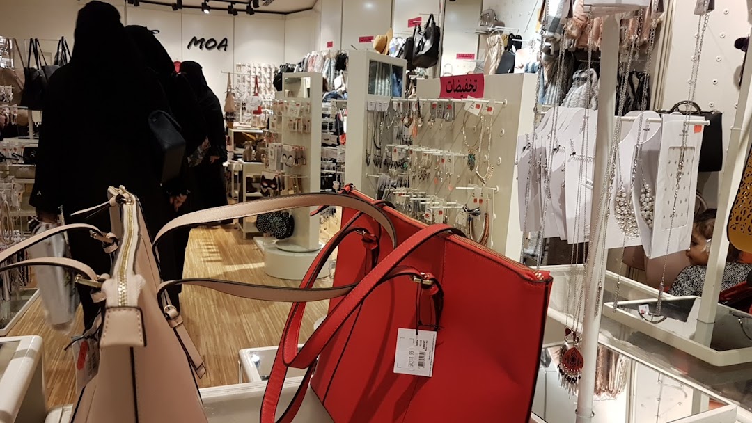 Interior view of a fashion accessories store with handbags and jewelry on display.