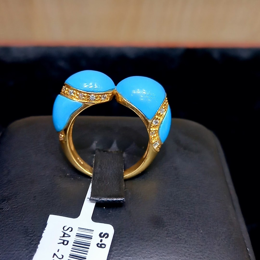 A gold ring with blue enamel and diamonds is displayed on a black stand.