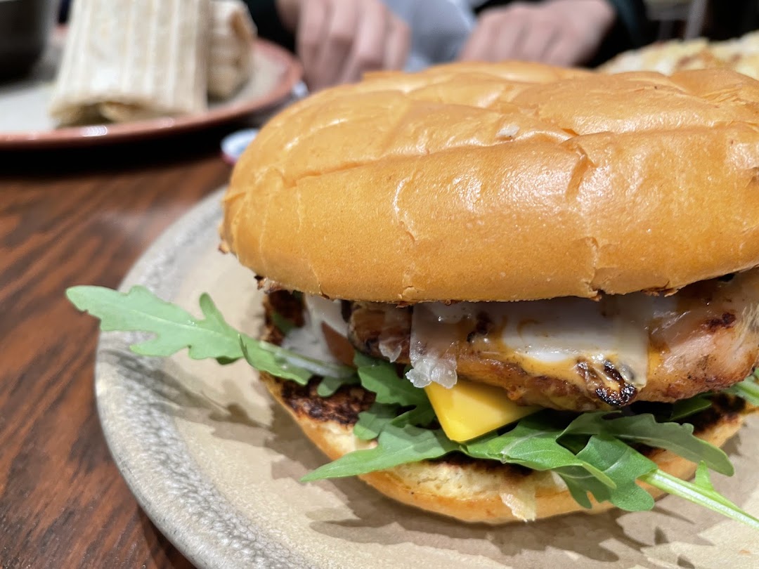 A close-up shot of a delicious chicken burger with melted cheese and fresh greens.