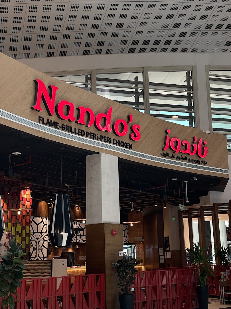 The exterior of a Nando's restaurant with its signature red and wood signage.