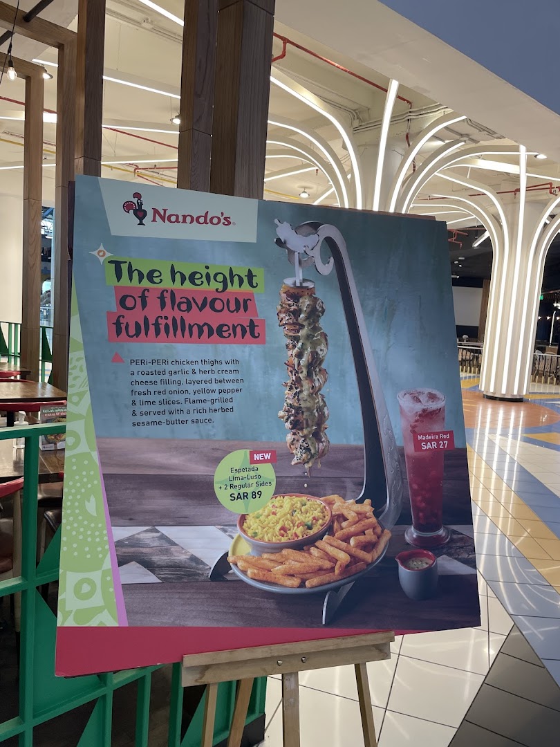 A Nando's promotional sign showcasing a chicken espetada meal and a drink.